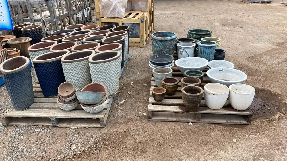 Assorted glazed garden pots displayed on pallets