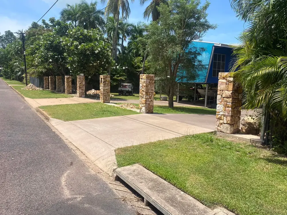 Completed natural stone gate posts beside a residential driveway